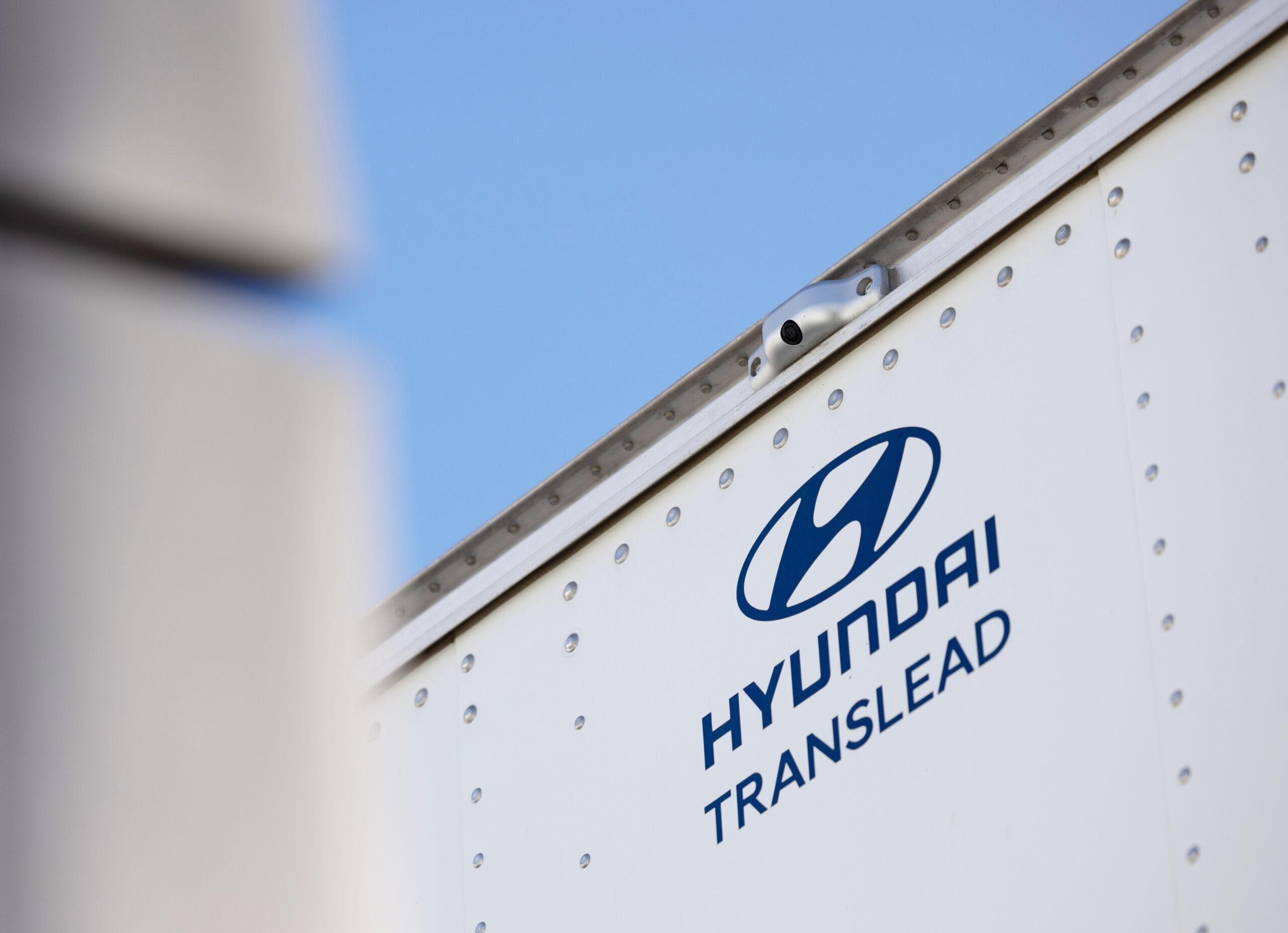 Close-up of the Hyundai Translead logo on a white trailer side, featuring an HT LinkVue camera system, highlighting Hyundai's innovation in trailer technology for improved visibility and incident recording.