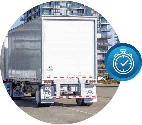 Rear view of a Hyundai Translead dry van trailer in a parking lot with a building in the background, accompanied by an icon representing lost service time, emphasizing how HT TEMPS trailer technology minimizes downtime and improves efficiency.