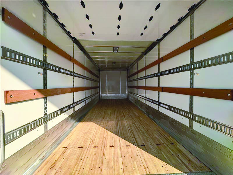 Interior perspective of a Hyundai Translead Anza truck body, showing the E-track system, wood floor, and sturdy walls, highlighting Hyundai's innovative truck body design and technology for secure cargo transport.