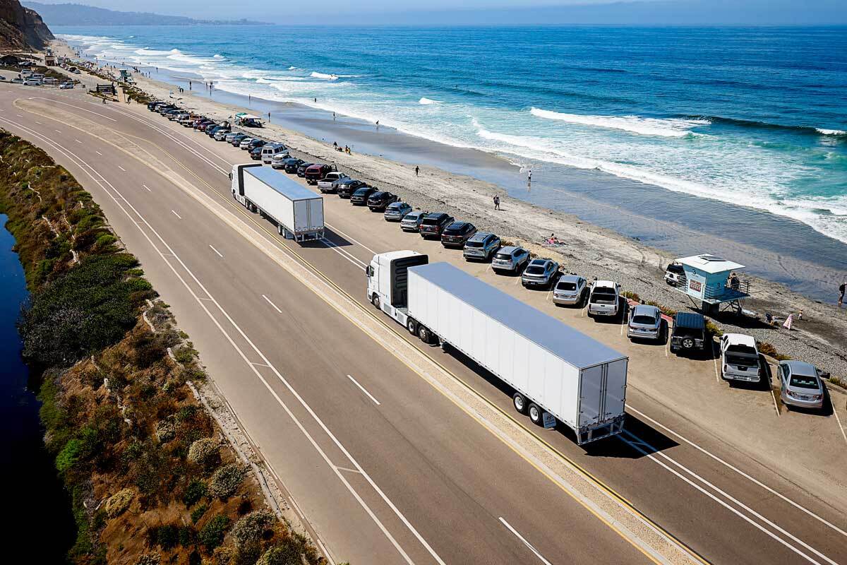 mobile-why-hyundai Two Hyundai Translead vehicles travel on a highway along the beach.